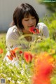 A woman in a field of red flowers with her eyes closed.