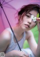 A woman holding a pink umbrella with a flower in her hand.