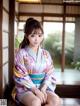 A woman in a kimono sitting on a wooden floor.