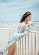 A woman in a blue and white dress leaning on a railing.