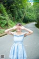 A woman in a blue and white dress covering her eyes with her hands.