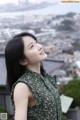 A woman in a green dress looking up at the sky.