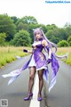 A woman in a purple dress is walking down the road.