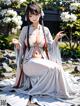 A woman in a white kimono sitting on the ground.