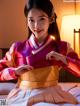 A woman in a pink and gold hanbok sitting on a bed.