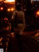 A woman walking down a city street at night.