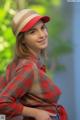 A woman wearing a red plaid shirt and a red hat.