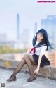 A woman in a school uniform sitting on a ledge.